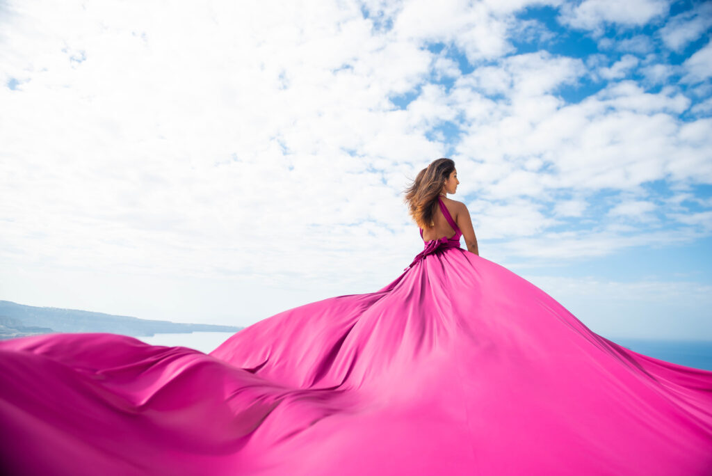 Woman looking over her shoulder in a purple flying dress beneath a dramatic sky