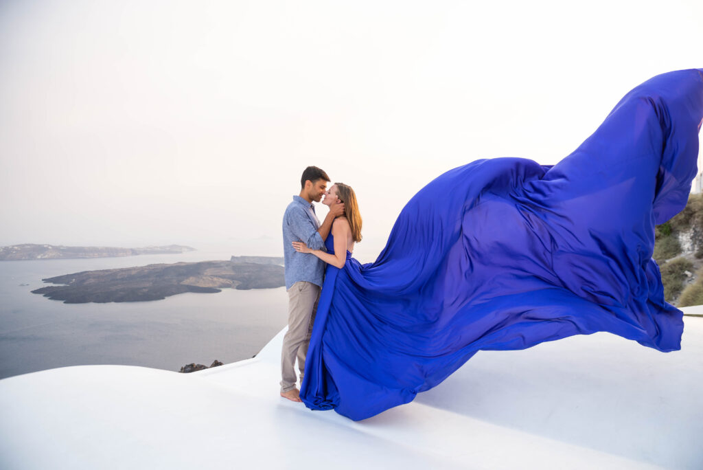 During a romantic moment, a couple stands with the woman wearing a flowing blue dress that moves with the gentle breeze. The image captures the beauty of the couple's affectionate embrace and the elegance of the dress, making for a stunning and enchanting moment that exudes love and romance.