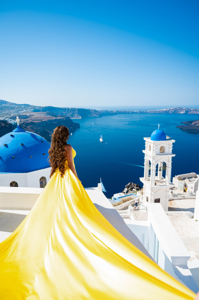 A lady in yellow floating dress with historic blue domes, church view.