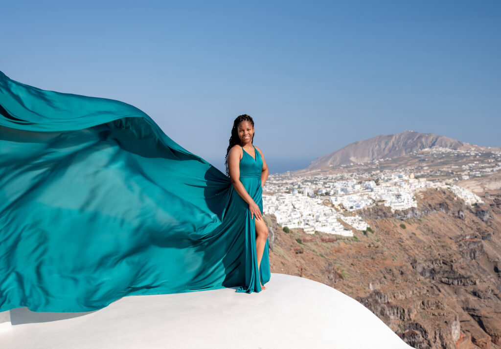 A magical photo of a woman wearing a stunning dress floating in the sky above the stunning Greek island of Santorini
