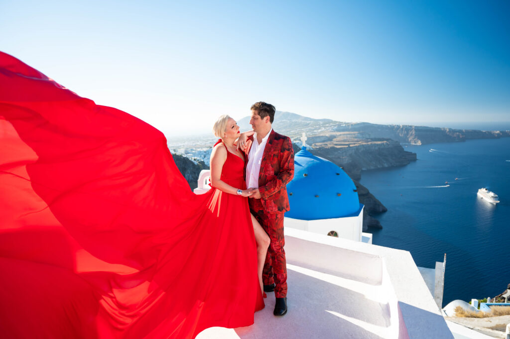 A magical photo of a woman, with her arms spread wide as if about to fly, against the stunning scenery of Santorini's volcanic landscape