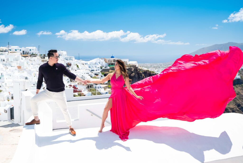 Couple holding hand and smiling at each other, the lady wears fuchsia flowing dress
