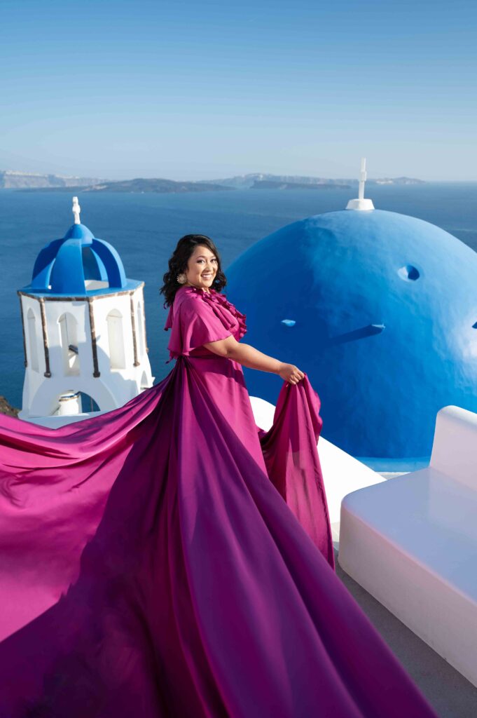Lady looking back in Santorini village in a flowing purple ruffled dress