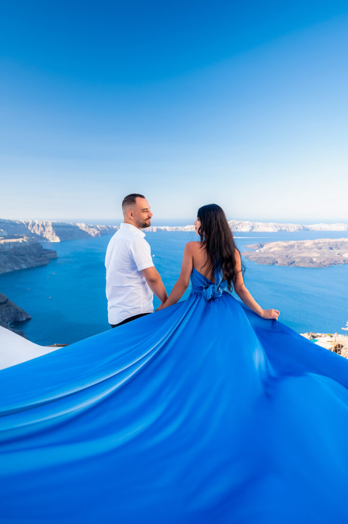A couple looking each other with their backs to the camera while a lady wear a sky blue flying dress.
