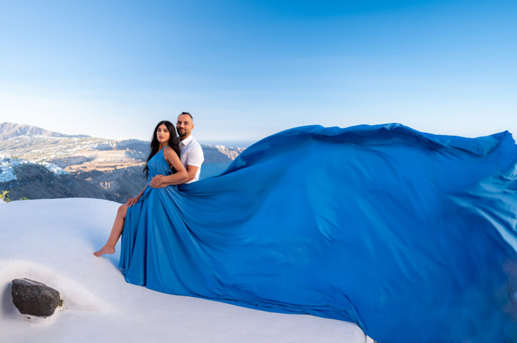 Husband and wife hugging and looking to the photographer with a cliff view in the background