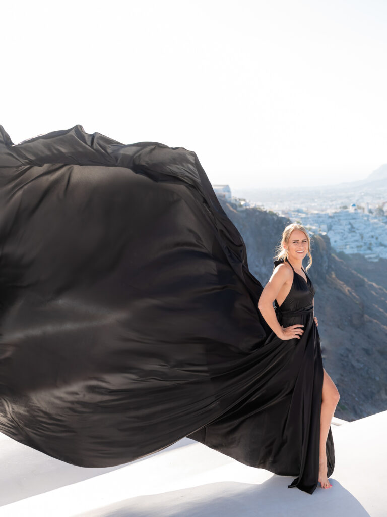 Girl standing on a roof with her hands on hips in black dress while looking the lens