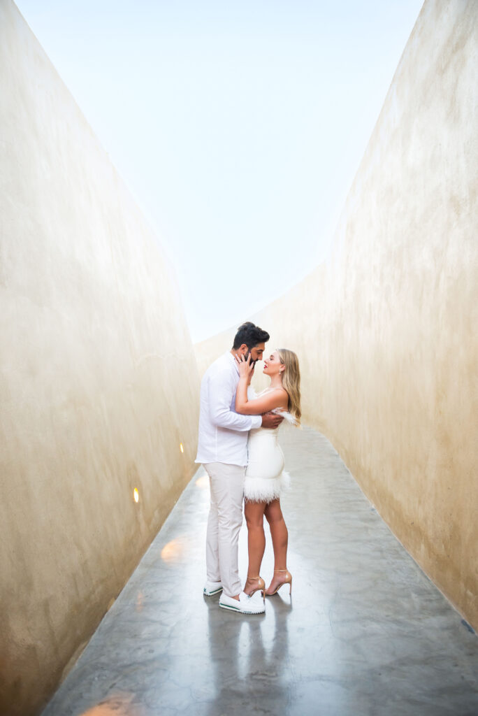 Couple in white hugging each other during a romantic moment in a gray long alley
