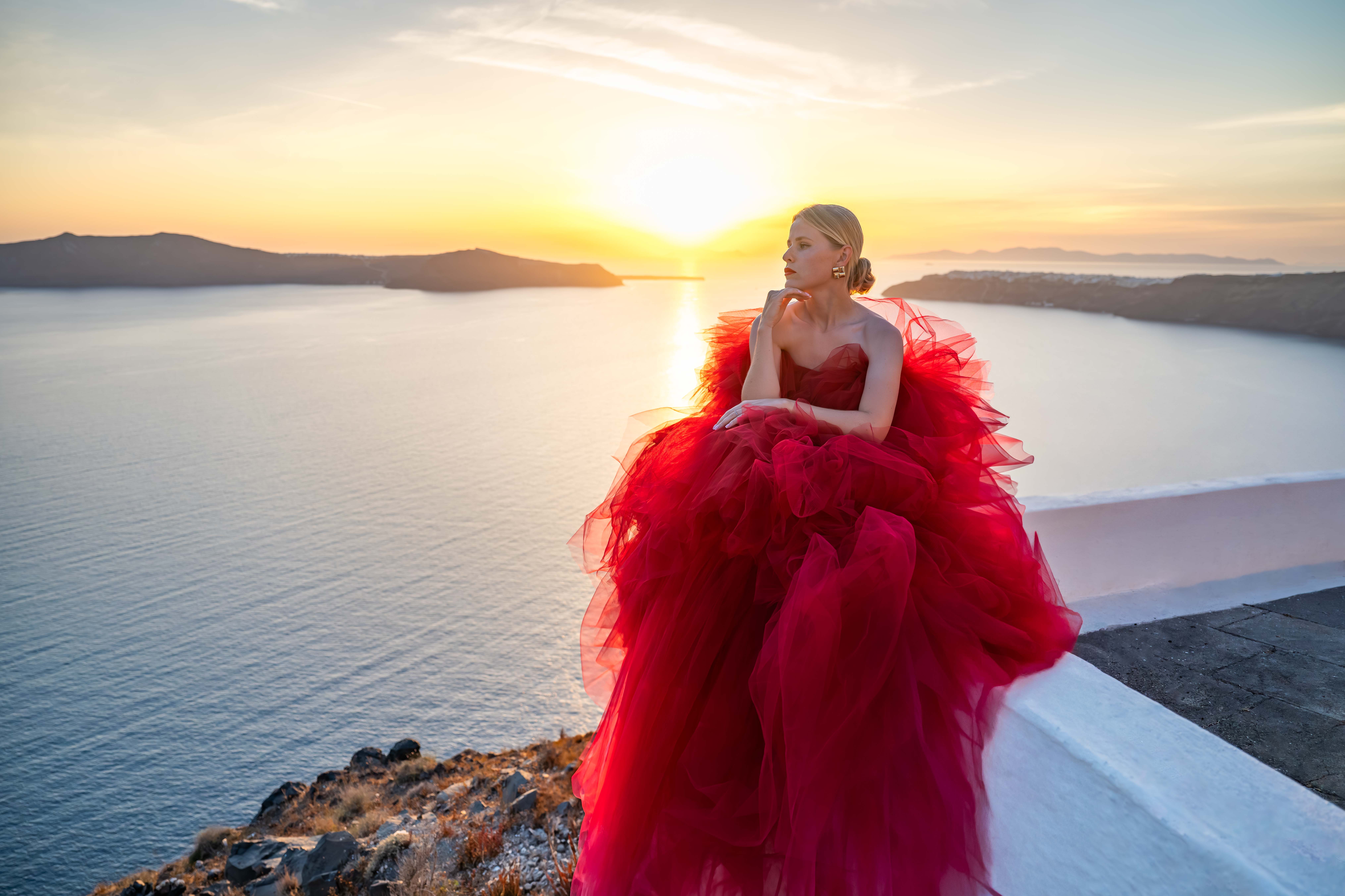Female sitting in a red fluffy attire looking away at volcano view
