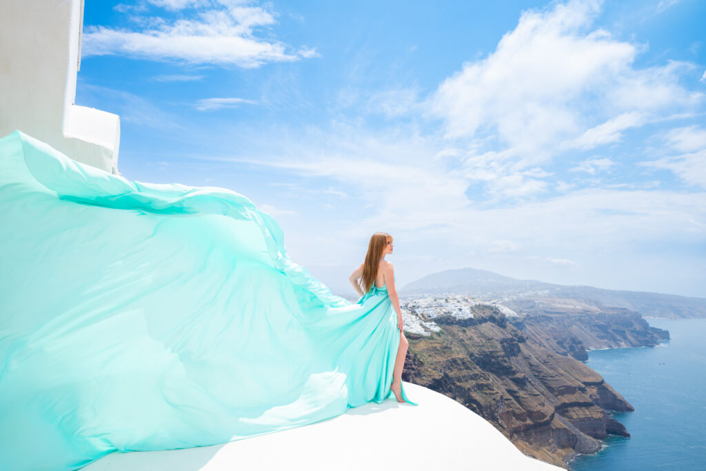 Young red hair woman posing on top of Caldera revealing stunning view to Fira town